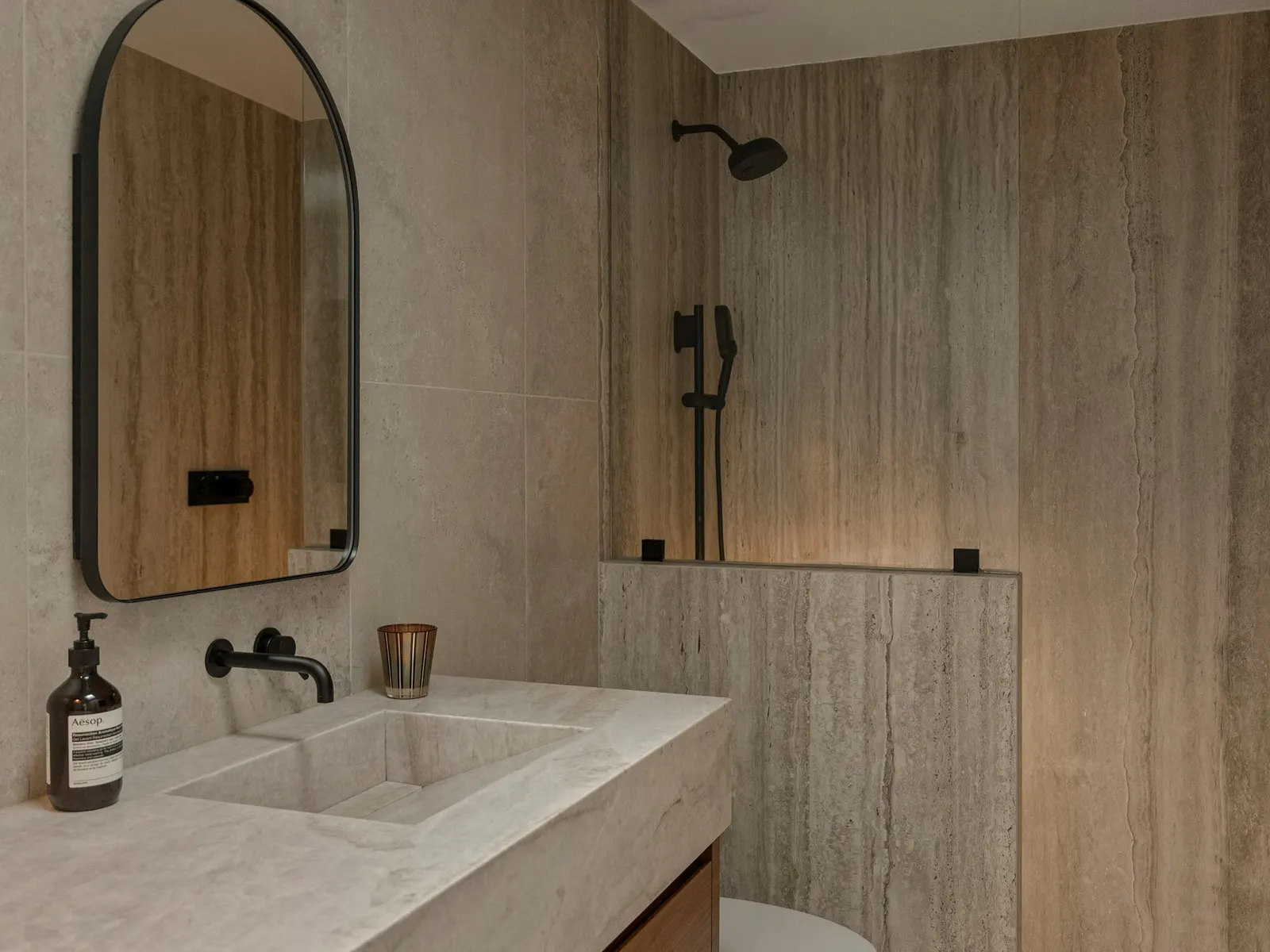 Stone surfaces and timber cabinetry in a representative bath setting